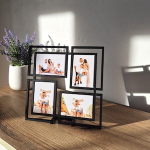 May include: A black multi-photo frame displaying four family photos. The frame is made of a geometric design and sits on a wooden surface. The photos feature families in various poses, capturing moments of togetherness.