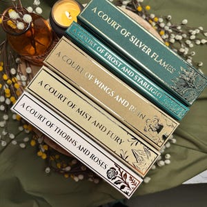 May include: A stack of four hardcover books with gold lettering and decorative floral designs. The titles include "A Court of Silver Flames," "A Court of Frost and Starlight," "A Court of Wings and Ruin," "A Court of Mist and Fury," and "A Court of Thorns and Roses."