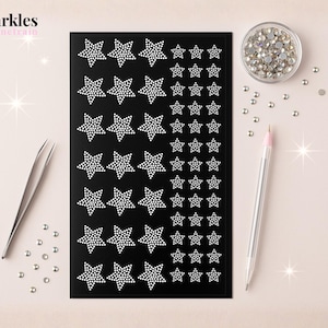 May include: A black sheet with star-shaped rhinestone stickers in various sizes. A small bowl of rhinestones, a pen, and tweezers are also present. The image has the text "Sparkles by junetrain" in the upper left corner.