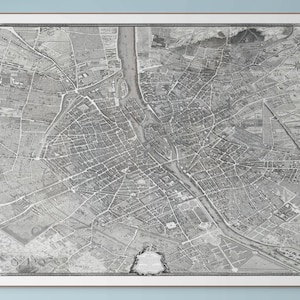 Puede incluir: Un mapa vintage en blanco y negro enmarcado de una ciudad, probablemente París, Francia. El mapa es detallado, mostrando calles, edificios y un río. El marco es blanco con un borde marrón fino. Es una pieza histórica.