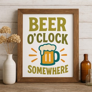 May include: A framed print with the words "BEER O'CLOCK SOMEWHERE" in green and yellow. The image includes a beer mug illustration with foam and radiating lines. The frame is brown, and the background is white.