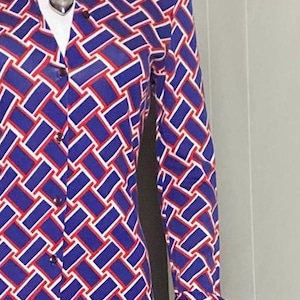 May include: A long-sleeved dress with a geometric pattern in shades of blue, red, and white. The dress has a collared neckline and button closure.