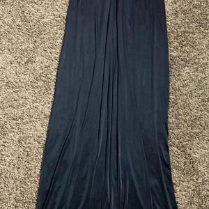 K&ouml;nnte beinhalten: Ein langes, dunkelmarineblaues Kleid mit V-Ausschnitt. Das Oberteil hat ein gerafftes Detail, und das Kleid flie&szlig;t bis zum Boden. Der Stoff scheint ein weiches, samtartiges Material zu sein.