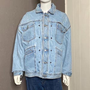 Könnte beinhalten: Eine hellblaue Jeansjacke mit Knopfleiste und mehreren Taschen. Die Jacke hat einen ausgewaschenen Look und ist aus einem weichen, bequemen Material gefertigt.
