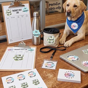 Może przedstawiać: Żółty Labrador Retriever w niebieskiej chuście z motywem "miłości", obok tablicy, butelki na wodę i torby na smakołyki. Przedmioty mają naklejki z napisami takimi jak "I have a pawsome friend" i "be pawsitive."