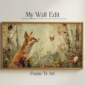 Puede incluir: Una obra de arte enmarcada que representa un zorro rojo mirando una mariposa naranja en un entorno forestal. La pintura tiene un marco dorado e incluye el texto "My Wall Edit" y "Frame Tv Art". Representa abedules, flores silvestres y mariposas.