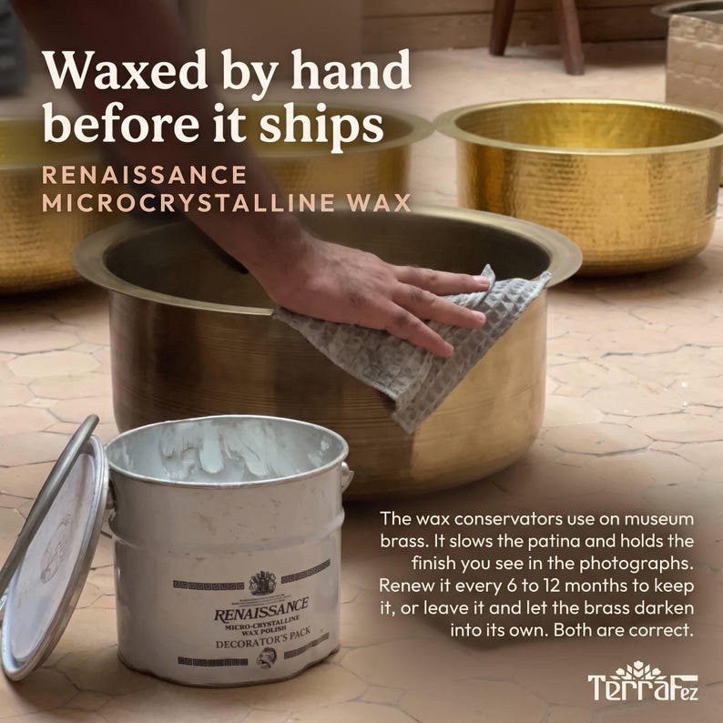 May include: A large, round, hammered brass basin with a metallic gold finish. A white metal tin of Renaissance Microcrystalline Wax Polish sits in the foreground, featuring a label with black text and a circular logo design.