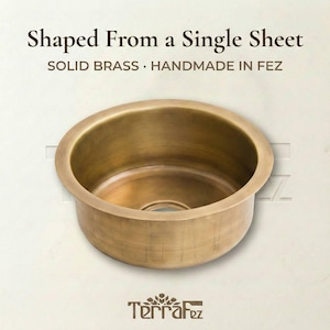 Side-angle view of TerraFez solid brass round sink showing seamless one-piece construction shaped from a single sheet, handmade in Fez, Morocco.