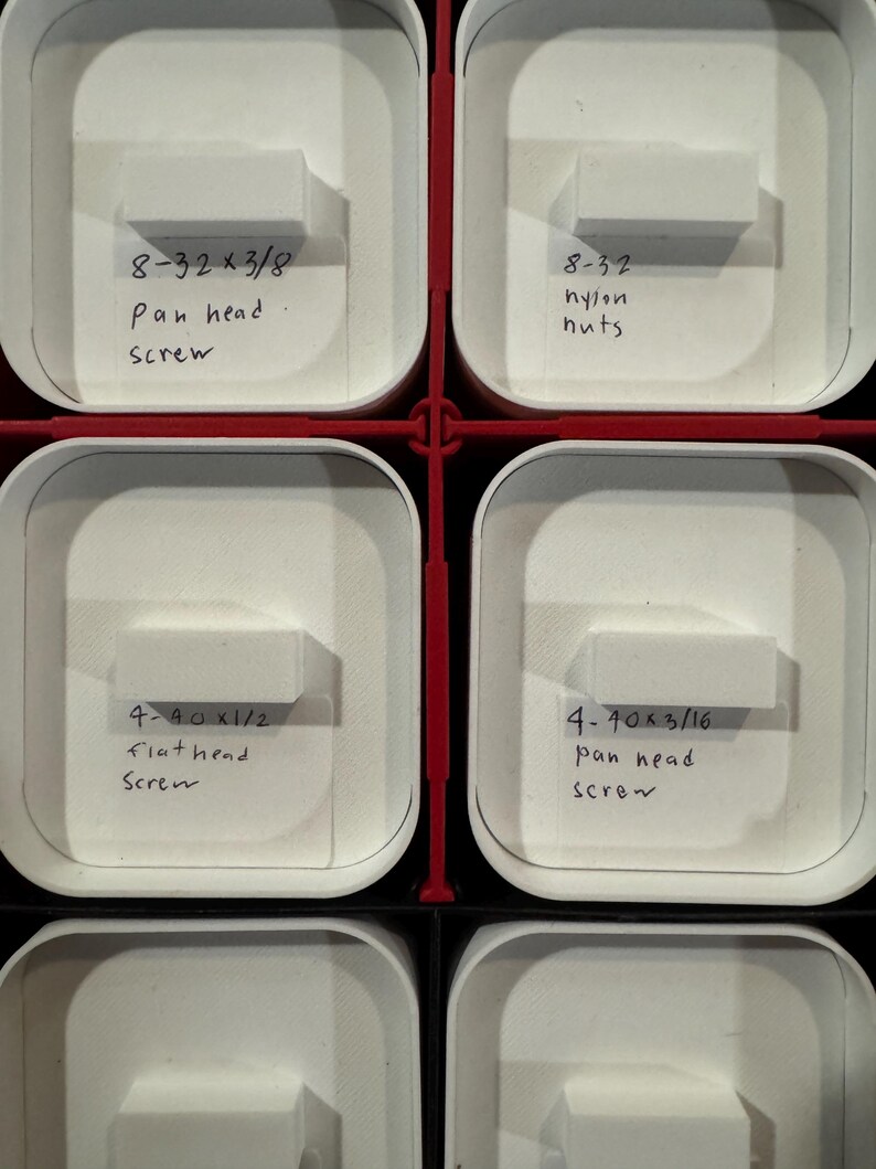 Puede incluir: Primer plano de un contenedor de almacenamiento con m&uacute;ltiples compartimentos blancos. Cada compartimento contiene peque&ntilde;os art&iacute;culos de ferreter&iacute;a y etiquetas manuscritas. Las etiquetas incluyen texto como "8-32 x 3/8 pan head screw" y "4-40 x 1/2 flat head screw."