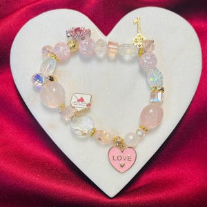 "Dieses 25 cm lange Armband ist mit einem ""Love""-Gesprächsherzanhänger, einem bejeweled Schlüsselanhänger und einem Liebesbriefanhänger versehen - das perfekte Valentinstagsgeschenk!"