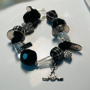 Sporty 9.5&quot; black & silver bracelet w/crystal and plaid beads, rhinestone buttons, &quot;Dream&quot; &quot;Hope&quot; and &quot;Hockey sticks/puck&quot; charms - Score!