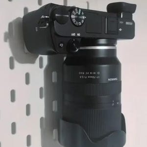 Puede incluir: Una cámara negra con un objetivo negro. El objetivo es un Tamron 17-70mm F/2.8 Di III-A VC RXD. La cámara tiene un cuerpo negro con un anillo plateado alrededor de la montura del objetivo.