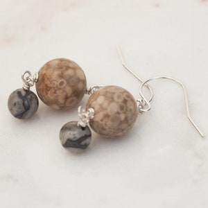 May include: A pair of dangle earrings with a brown and white patterned stone and a smaller black and white stone on each earring.