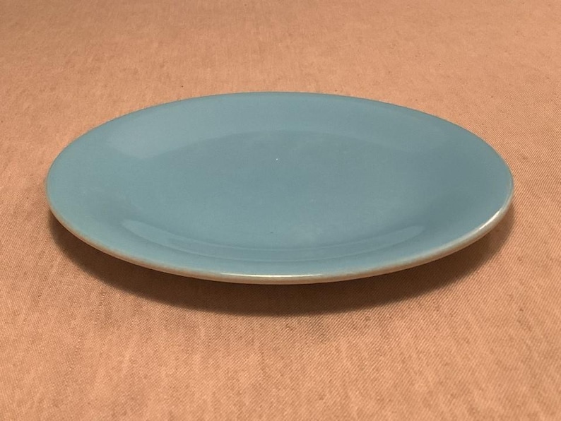 Pu&ograve; includere: Un piatto ovale in ceramica azzurra con un bordo leggermente rialzato. Il piatto ha una finitura liscia e lucida. Adatto per servire cibo.