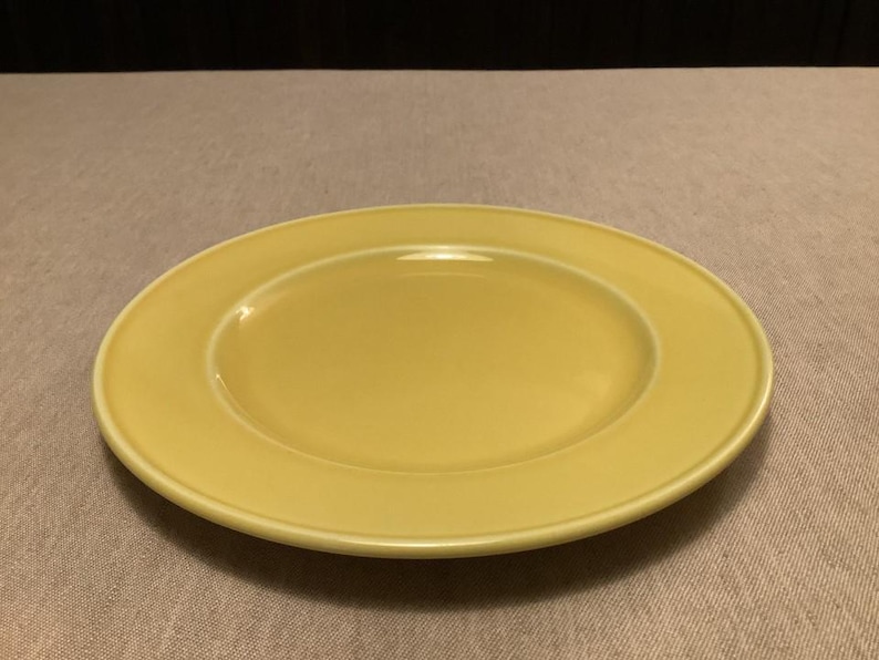 Pu&ograve; includere: Un piatto rotondo in ceramica gialla con un bordo leggermente rialzato. Il piatto ha una finitura liscia e lucida ed &egrave; posto su uno sfondo neutro. Questo piatto &egrave; adatto per servire i pasti.