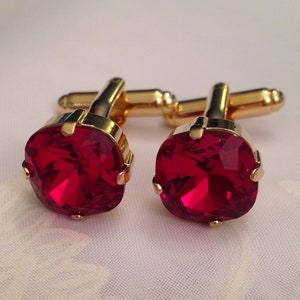 May include: A pair of gold cufflinks with red gemstone accents. The cufflinks have a classic design and are perfect for adding a touch of elegance to any outfit.
