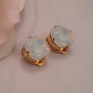 May include: A pair of gold tone clip-on earrings with large, square, iridescent white opal stones.