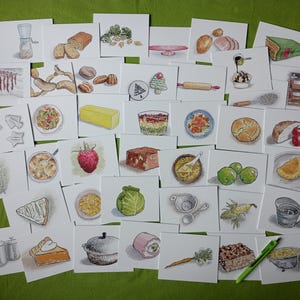 May include: A collection of watercolor illustrations of various food items, including bread, vegetables, and desserts, arranged on a green surface. The illustrations are on individual white cards, showcasing a variety of culinary subjects.