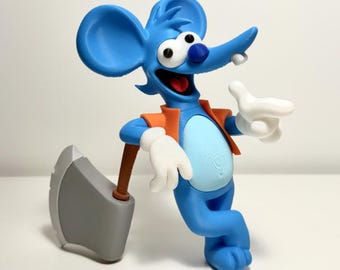 May include: A blue cartoon mouse figurine with large ears, a light blue belly, and white gloves. The mouse wears an orange vest, has a wide grin with a single tooth, and leans against a large gray axe with a brown handle.