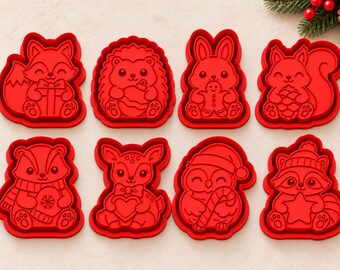 May include: A set of eight red plastic cookie cutters featuring various woodland animals including a fox with a gift, a hedgehog, a rabbit with a gingerbread man, a squirrel with a pinecone, a badger, a deer, an owl, and a raccoon.