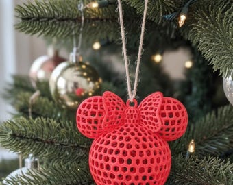 May include: A bright red, 3D-printed Christmas ornament featuring a spherical base and two circular ears, all with a hollow, interconnected honeycomb lattice structure. A small bow sits between the ears, and a tan twine loop is attached for hanging.