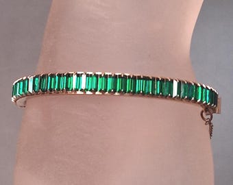 Bracciale rigido con cerniera e strass a baguette di smeraldo.