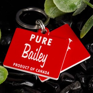 May include: Red rectangular dog tag with a silver key ring. The tag says "PURE Bailey PRODUCT OF CANADA" in white lettering.