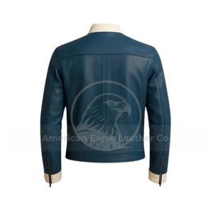 May include: A dark teal leather jacket with a cream-colored collar and cuffs. The back of the jacket is visible, showcasing a classic design with a zipper on each sleeve. The text "American Eagle Leather Co" is printed on the jacket.