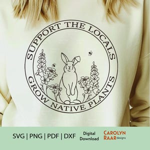 Puede incluir: Sudadera crema con un diseño circular que presenta un conejo, flores y el texto "SUPPORT THE LOCALS GROW NATIVE PLANTS" en blanco y negro. Debajo del diseño, se indican los tipos de archivo SVG, PNG, PDF y DXF.