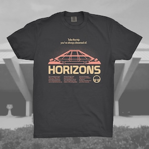 May include: Dark gray t-shirt with a retro-style graphic. The design features the word "HORIZONS" in a bold, peach-colored font, along with an illustration of a futuristic building and the text "Take the trip you've always dreamed of."