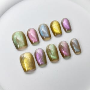 May include: Set of ten iridescent press-on nails in various shades of green, pink, gold, and blue.