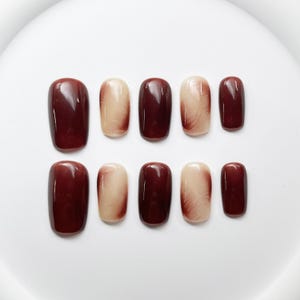 May include: Set of ten false nails with a brown and cream ombre design. The nails are short and square shaped.