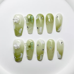 May include: Set of ten green and white ombre press-on nails with various embellishments, including butterflies, flowers, and rhinestones.