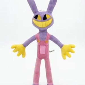 May include: A plush toy shaped like a purple rabbit with long ears, yellow hands, and a wide yellow grin. The character wears pink overalls with yellow buttons and a small square pocket on the front. The fabric has a soft, smooth texture throughout.
