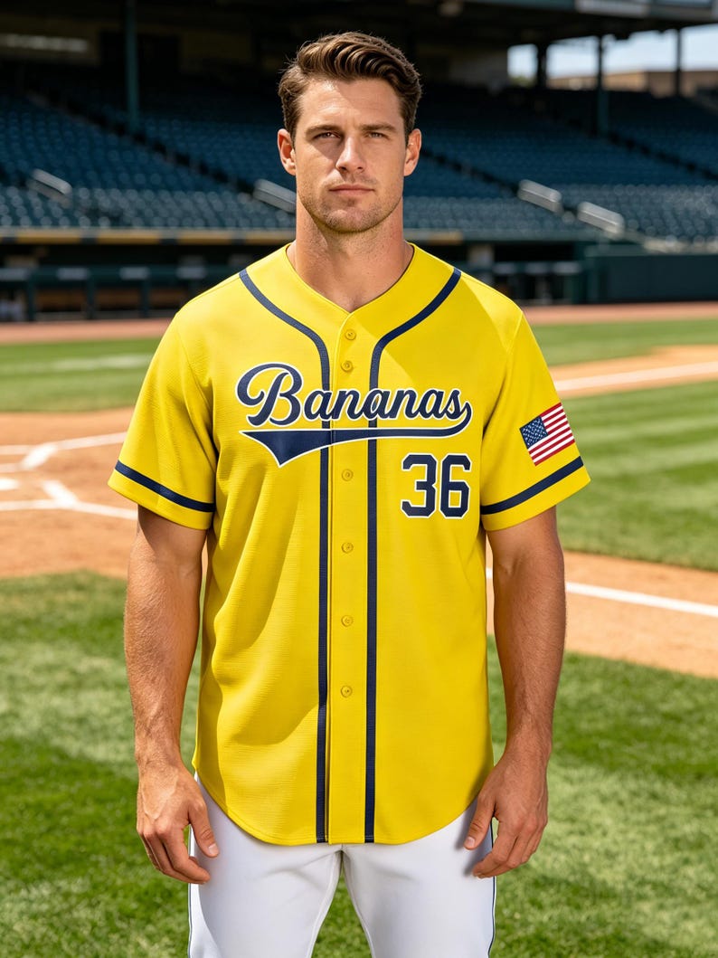 May include: A yellow baseball jersey with dark blue trim, featuring the word Bananas in script font across the chest, the number 36 below it, and a small American flag patch on the left sleeve. The button-down shirt has a rounded hemline.