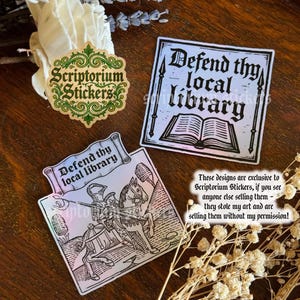 May include: A selection of stickers with a medieval theme. One sticker displays the text "Defend thy local library" with an illustration of a knight on horseback. Another sticker has the same text with an open book illustration. A third sticker has the "Scriptorium Stickers" logo.