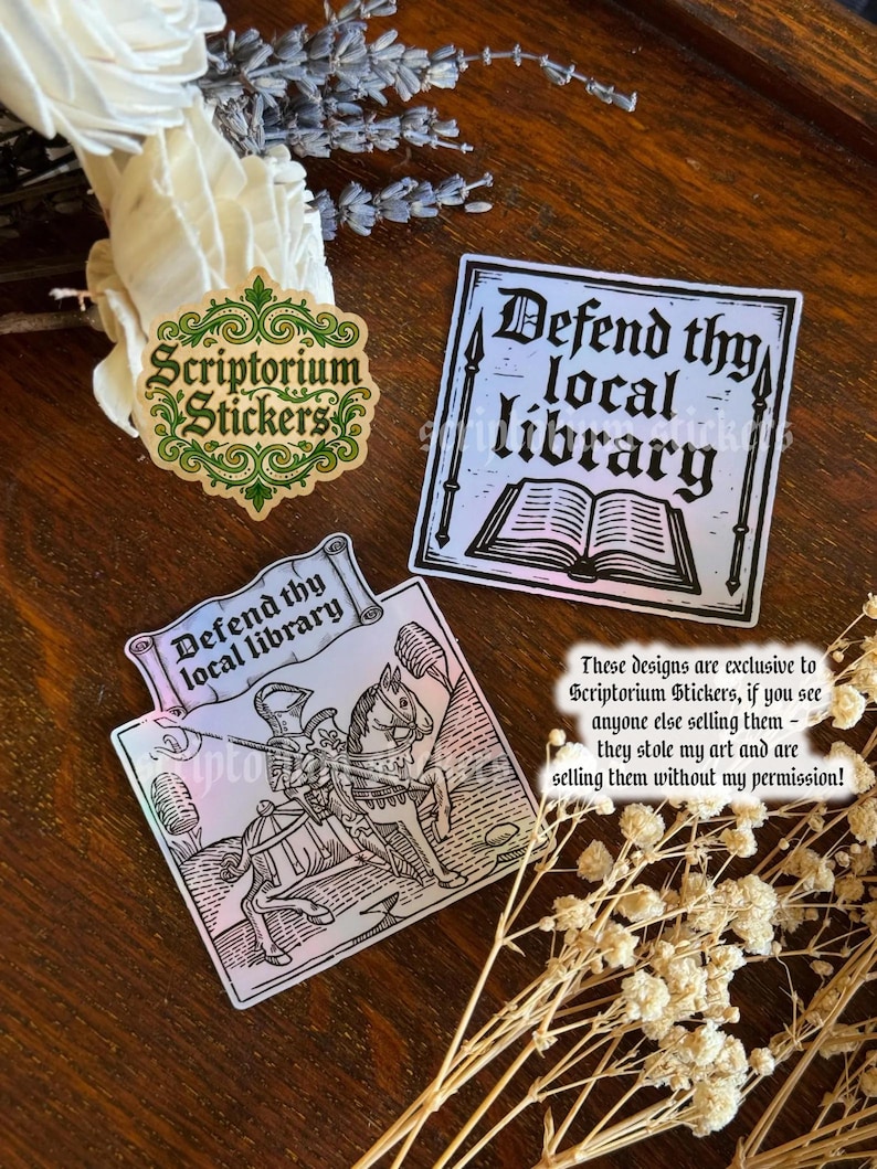 May include: A selection of stickers with a medieval theme. One sticker displays the text "Defend thy local library" with an illustration of a knight on horseback. Another sticker has the same text with an open book illustration. A third sticker has the "Scriptorium Stickers" logo.