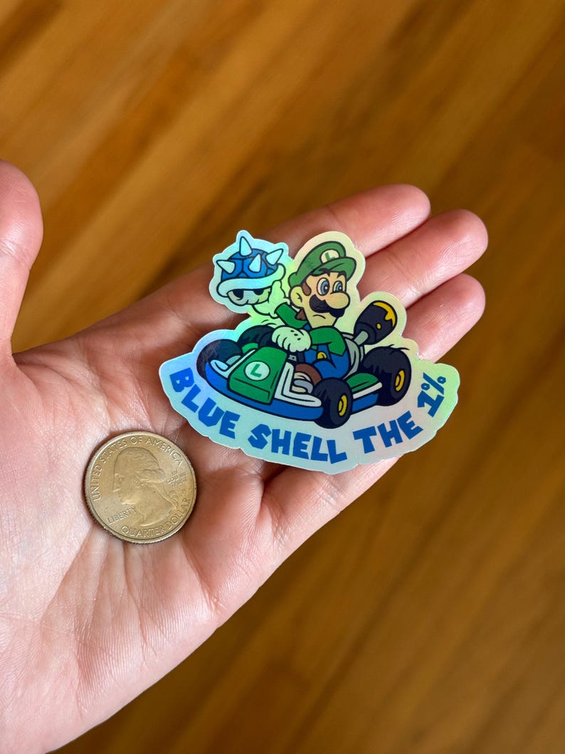 May include: A holographic sticker featuring a green-clad Mario character driving a kart with a blue shell. The sticker reads "Blue Shell the 1%".