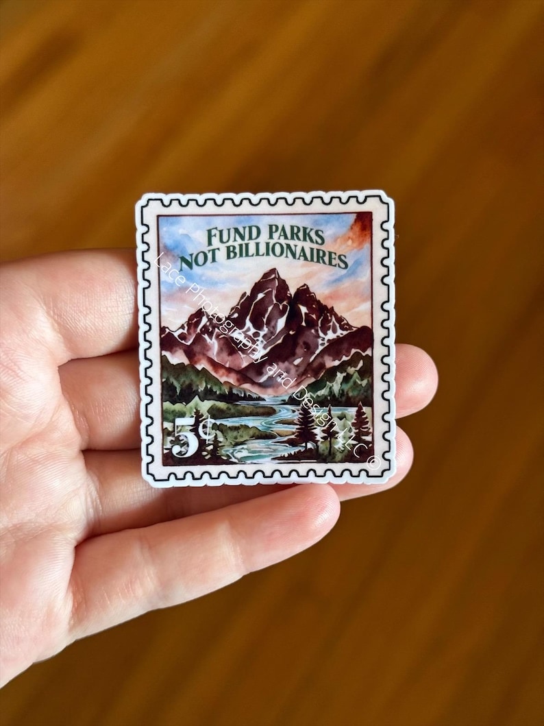 May include: A sticker resembling a vintage postage stamp, featuring a watercolor landscape of mountains, a river, and trees. The text "FUND PARKS NOT BILLIONAIRES" is at the top, with a "5&cent;" value in the corner.