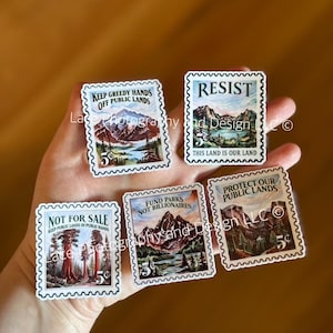 May include: A collection of five rectangular stickers resembling postage stamps. Each stamp features a landscape scene and text such as "Keep Greedy Hands Off Public Lands" and "Resist". The stamps have a serrated edge and a 5&cent; value.