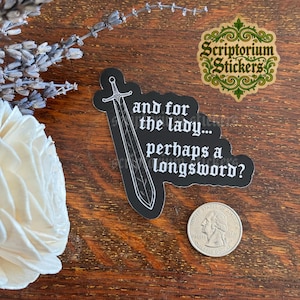 May include: A black die-cut sticker featuring a white line-art illustration of a longsword and the text, "and for the lady... perhaps a longsword?" The sticker is positioned next to a United States quarter coin for scale, showing the relative size.