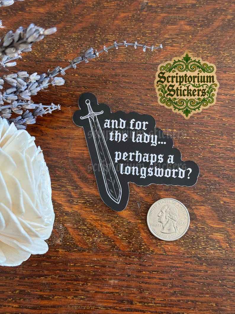 May include: A black die-cut sticker featuring a white line-art illustration of a longsword and the text, "and for the lady... perhaps a longsword?" The sticker is positioned next to a United States quarter coin for scale, showing the relative size.