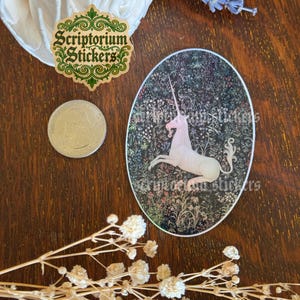 May include: An oval sticker featuring a white unicorn against a dark floral background. The sticker has the text "Scriptorium Stickers" and is surrounded by other decorative elements, including a coin and dried flowers.