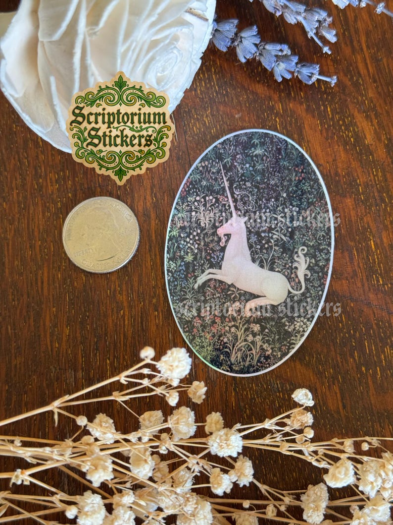 May include: An oval sticker featuring a white unicorn against a dark floral background. The sticker has the text "Scriptorium Stickers" and is surrounded by other decorative elements, including a coin and dried flowers.