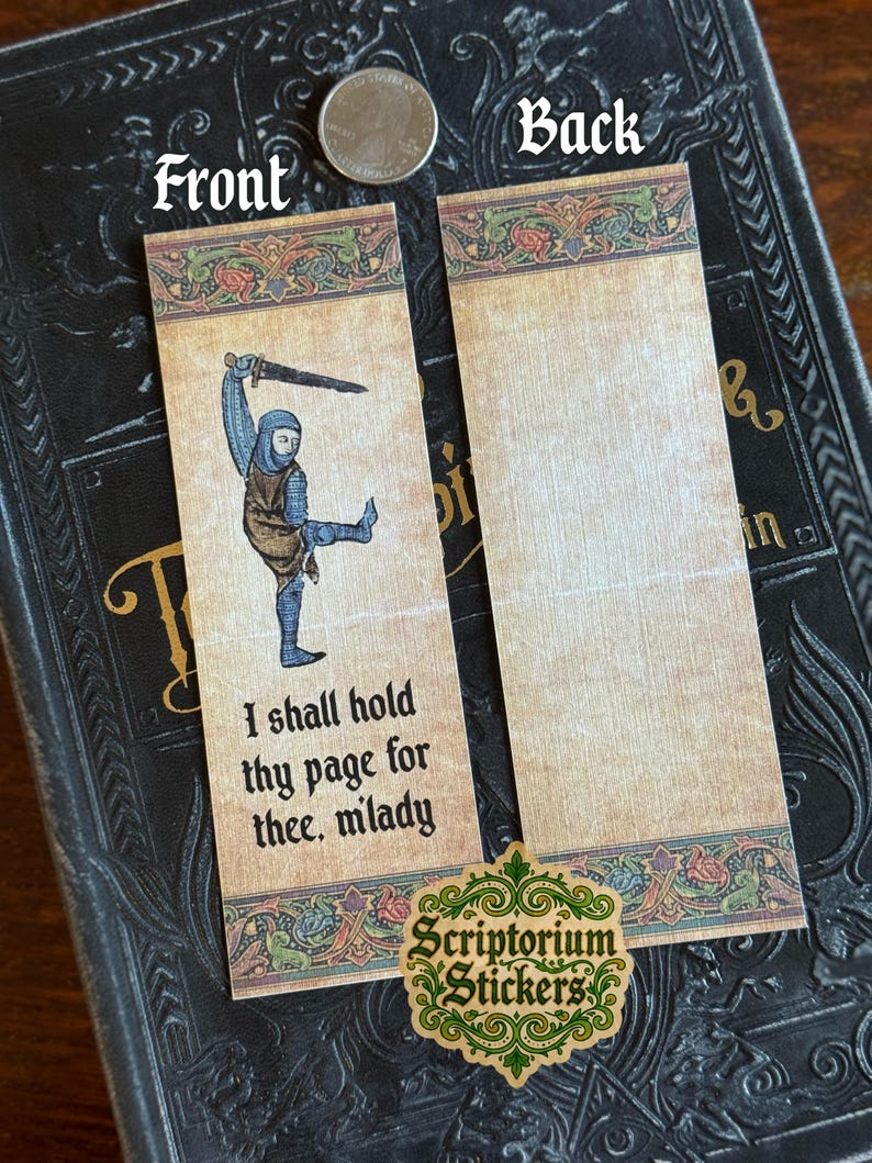 May include: Two medieval-themed bookmarks. The front bookmark features a knight illustration with the text "I shall hold thy page for thee, milady." The back bookmark is blank. The bookmarks are on a dark book.