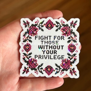 May include: A white sticker with a floral border and the text "FIGHT FOR THOSE WITHOUT YOUR PRIVILEGE". The design features pixelated pink roses and black leaves. The sticker has a holographic, iridescent finish.