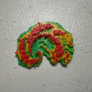 May include: A 3D printed object shaped like a seahorse with a green, yellow, and red color scheme.
