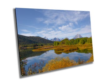 May include: A scenic landscape photograph featuring a mountain range reflected in a still lake. The mountains are covered in snow and the lake is surrounded by trees with fall foliage.