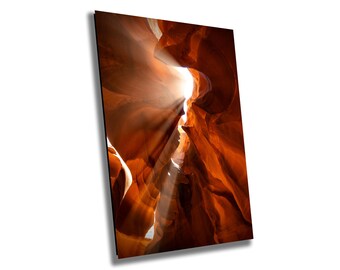May include: A narrow canyon with orange and red rock walls. Sunlight streams through the opening at the top of the canyon, creating a bright, glowing effect.