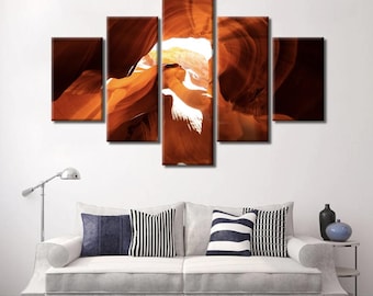 May include: A five-piece canvas print set featuring a photograph of a canyon with a bright light shining through the opening. The canyon walls are a deep orange and red color.